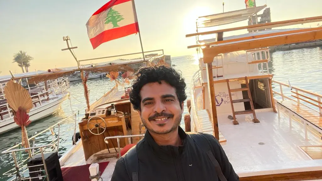 Kalpesh is smiling in a wide angle selfie with roman ruins in the background